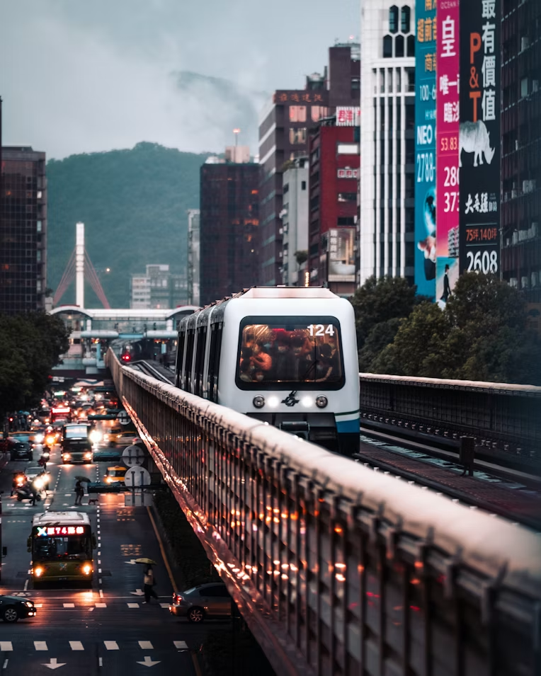 A Taipei metro train moving through the city at night in the rain