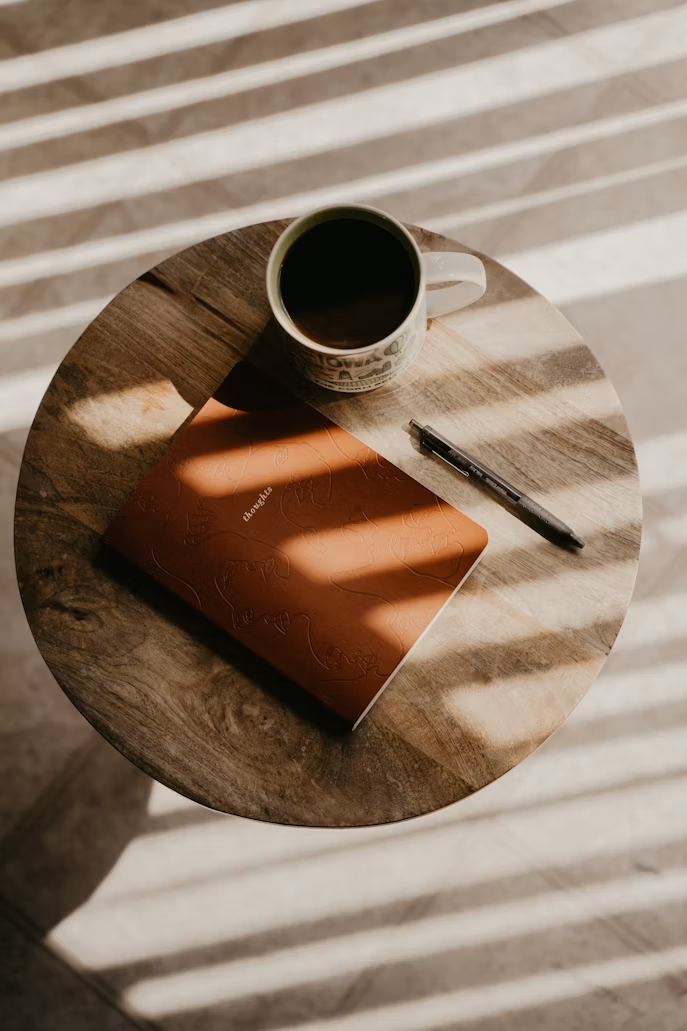 Morning light and shadow across a notebook and coffee cup
